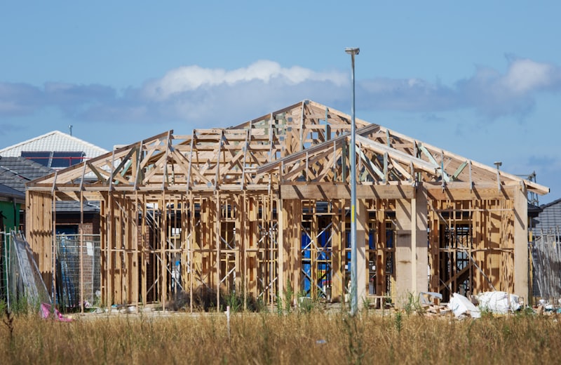 Full house frame under construction against a clear blue sky
