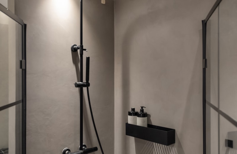Modern bathroom with matte black rain shower fixtures and concrete-look walls