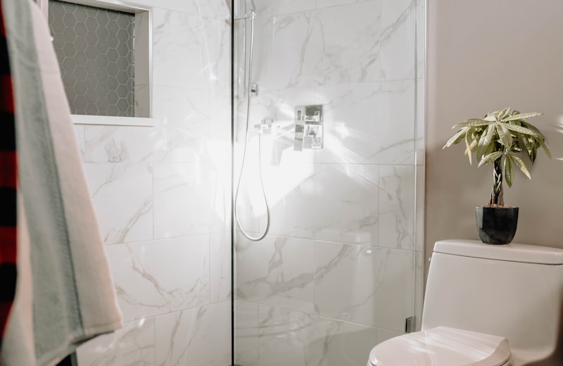 Marble-tiled glass shower next to a modern toilet and vanity area