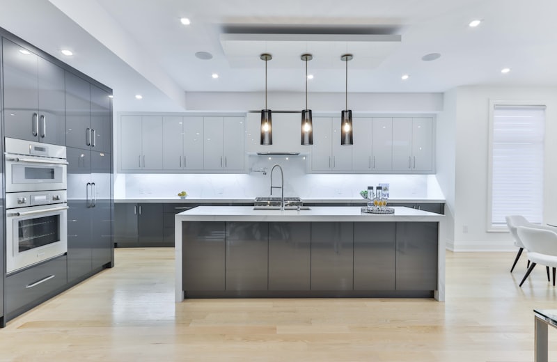 Modern kitchen with dark gray cabinetry, a waterfall island and pendant lighting