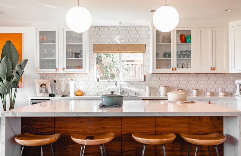 Kitchen with white cabinetry, a marble island and leather counter stools