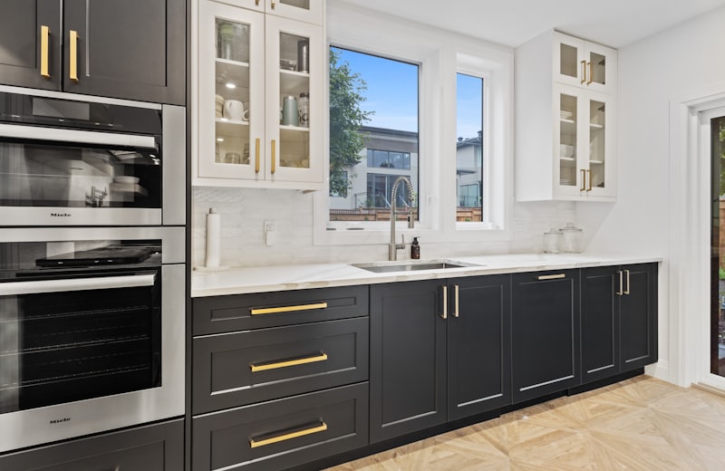 Two-tone kitchen with navy lower cabinets, white uppers and brass hardware