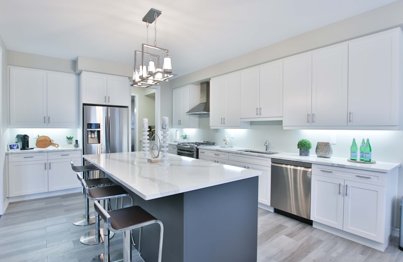 Bright white kitchen with a large center island and pendant chandelier