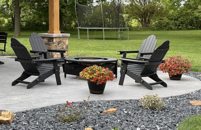 Backyard fire pit with Adirondack chairs and a stone-clad patio post