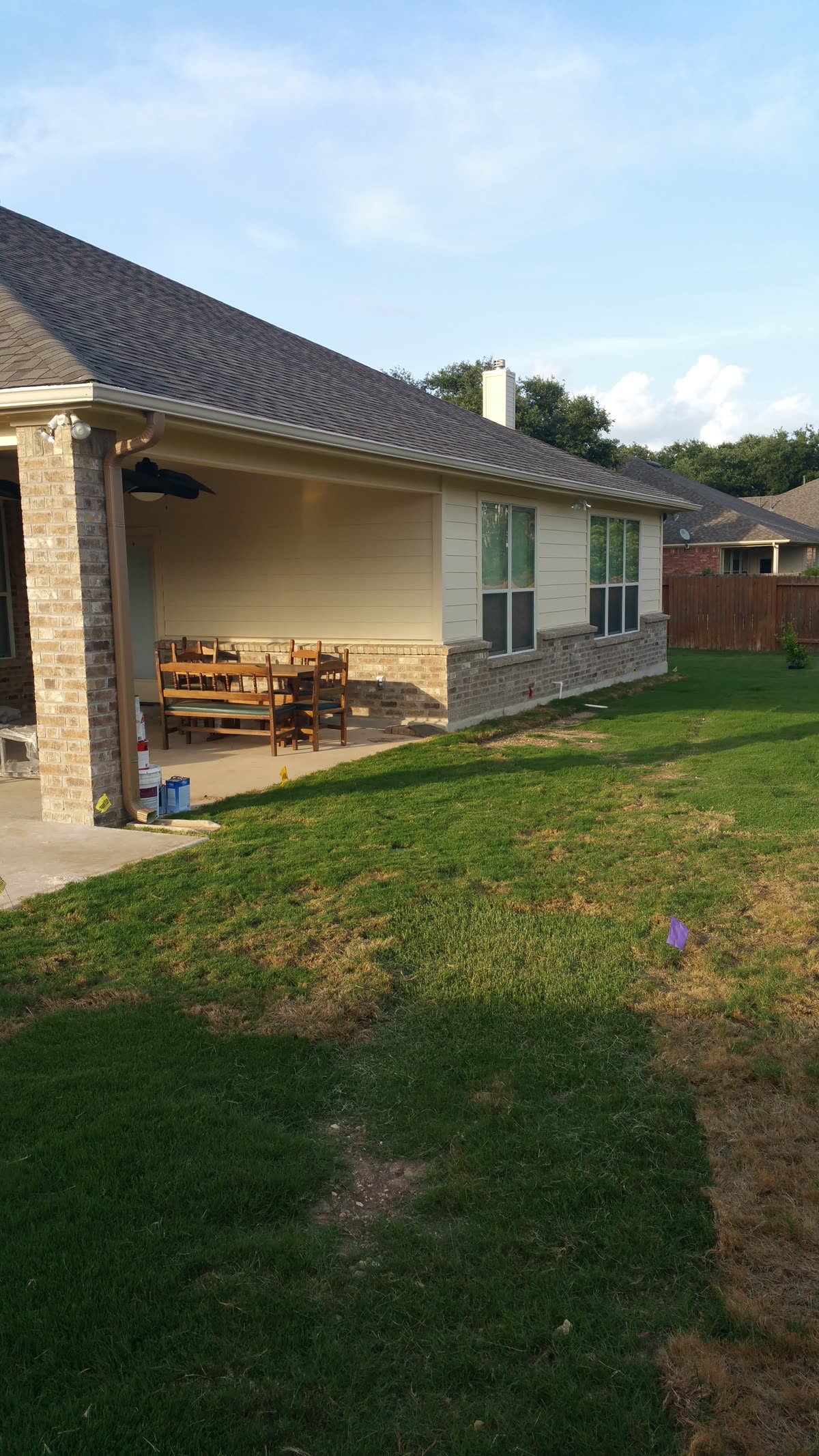 Covered back patio with a dining table and view across the backyard